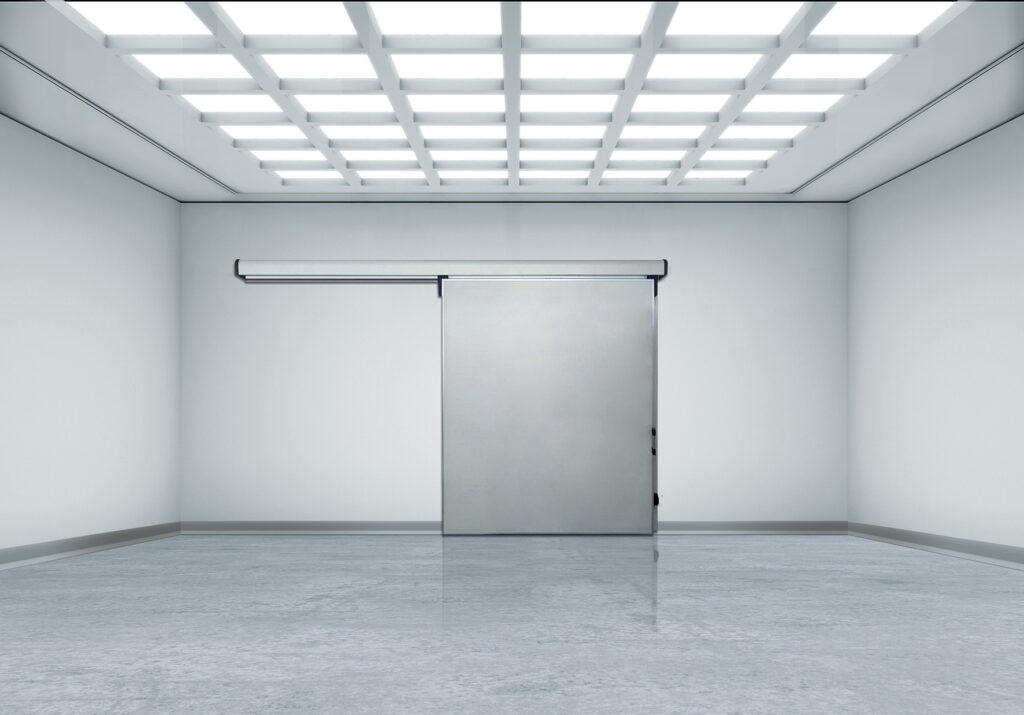 Sterile white room with grid lights and a sliding stainless door.