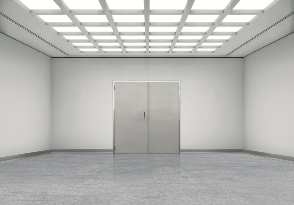 Empty white room with grid ceiling lights and metal double doors