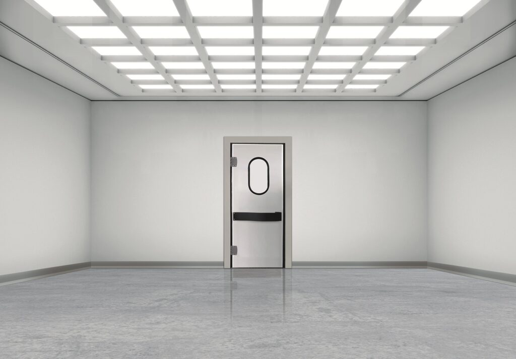 Sterile empty room with grid lights and a metal door with oval window