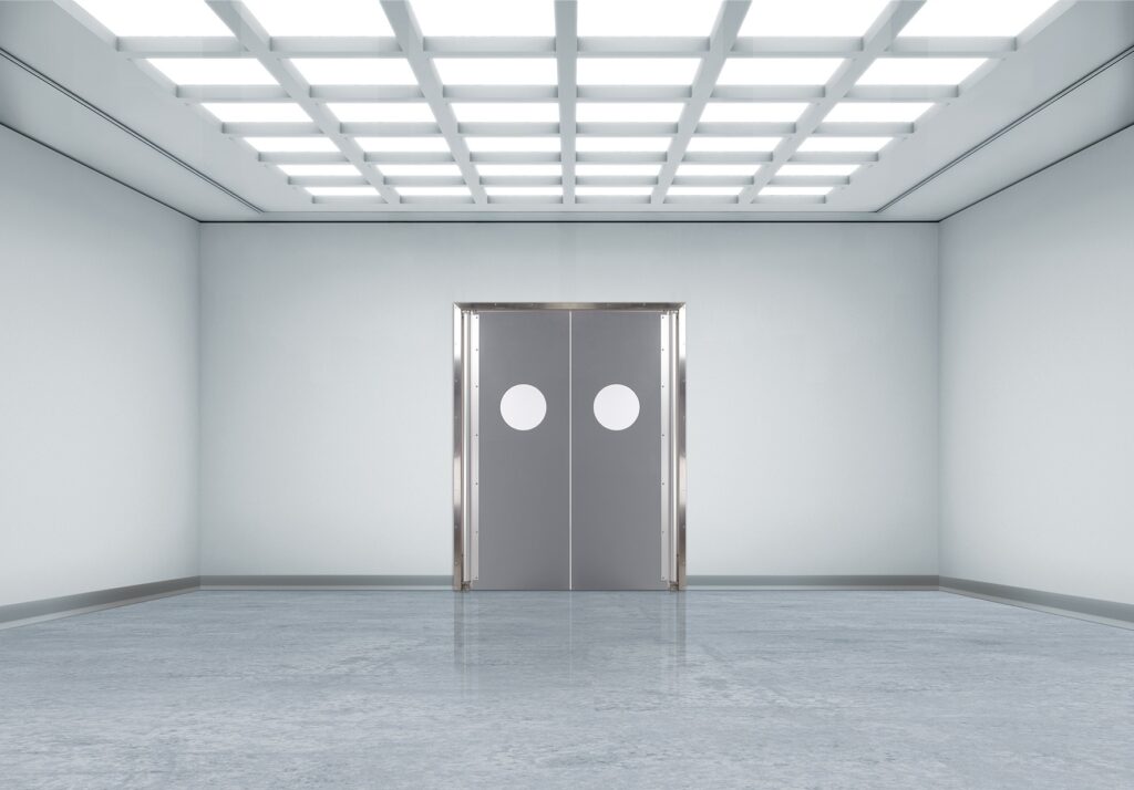 Bright sterile hallway with gray double doors and round windows.