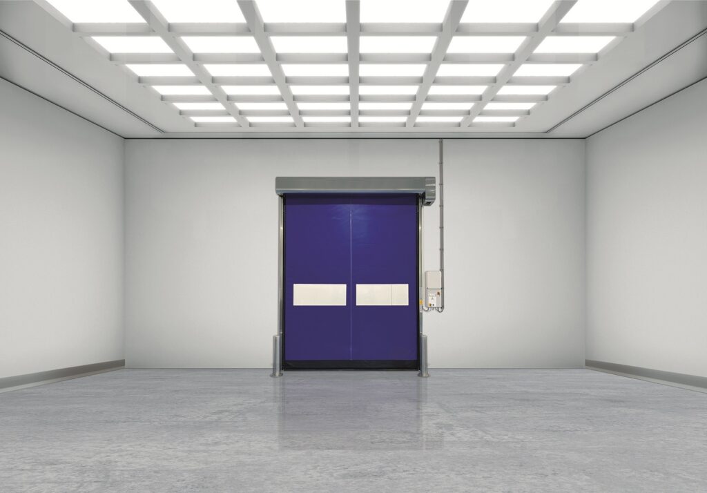 Bright cleanroom with a blue high-speed roll-up door centered
