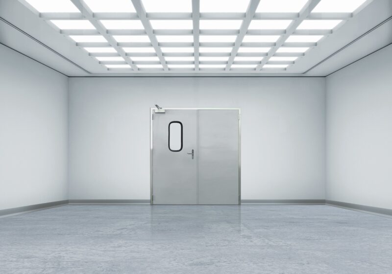 Sterile white room with metal double doors and grid ceiling lights